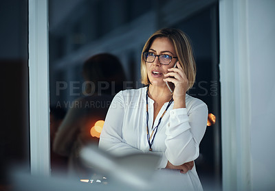 Buy stock photo Shot of a businesswoman talking on a mobile phone during a late night at work