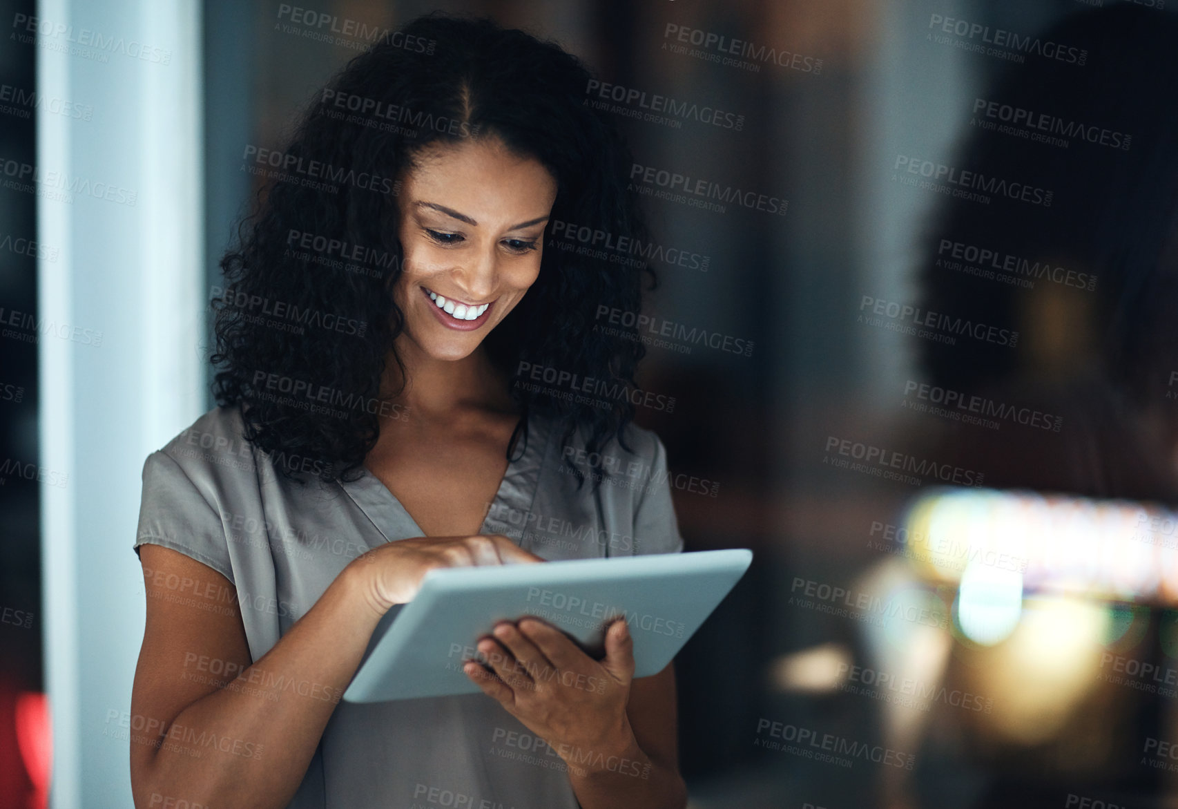 Buy stock photo Shot of a young businesswoman using a digital tablet during a late night at work