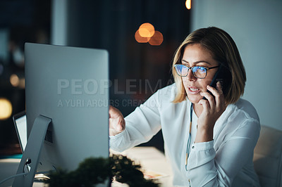 Buy stock photo Shot of a businesswoman using a computer and talking on the phone during a late night at work