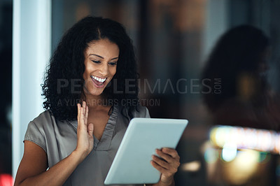 Buy stock photo Shot of a young businesswoman using a digital tablet during a late night at work and waving