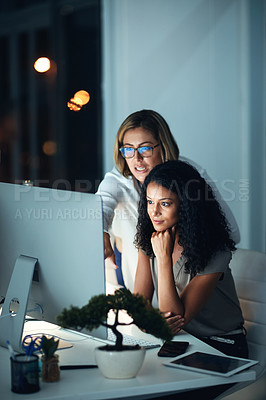 Buy stock photo Shot of two colleagues using a computer together during a late night at work