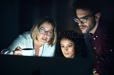 Buy stock photo Shot of a group of colleagues using a computer together during a late night at work