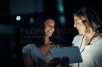 Buy stock photo Shot of two colleagues using a digital tablet together during a late night at work