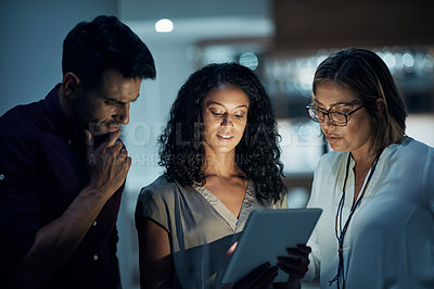 Buy stock photo Shot of a group of colleagues using a digital tablet together during a late night at work