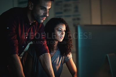 Buy stock photo Shot of two colleagues using a computer together during a late night at work