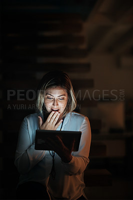 Buy stock photo Shot of a businesswoman using a digital tablet during a late night at work and looking shocked