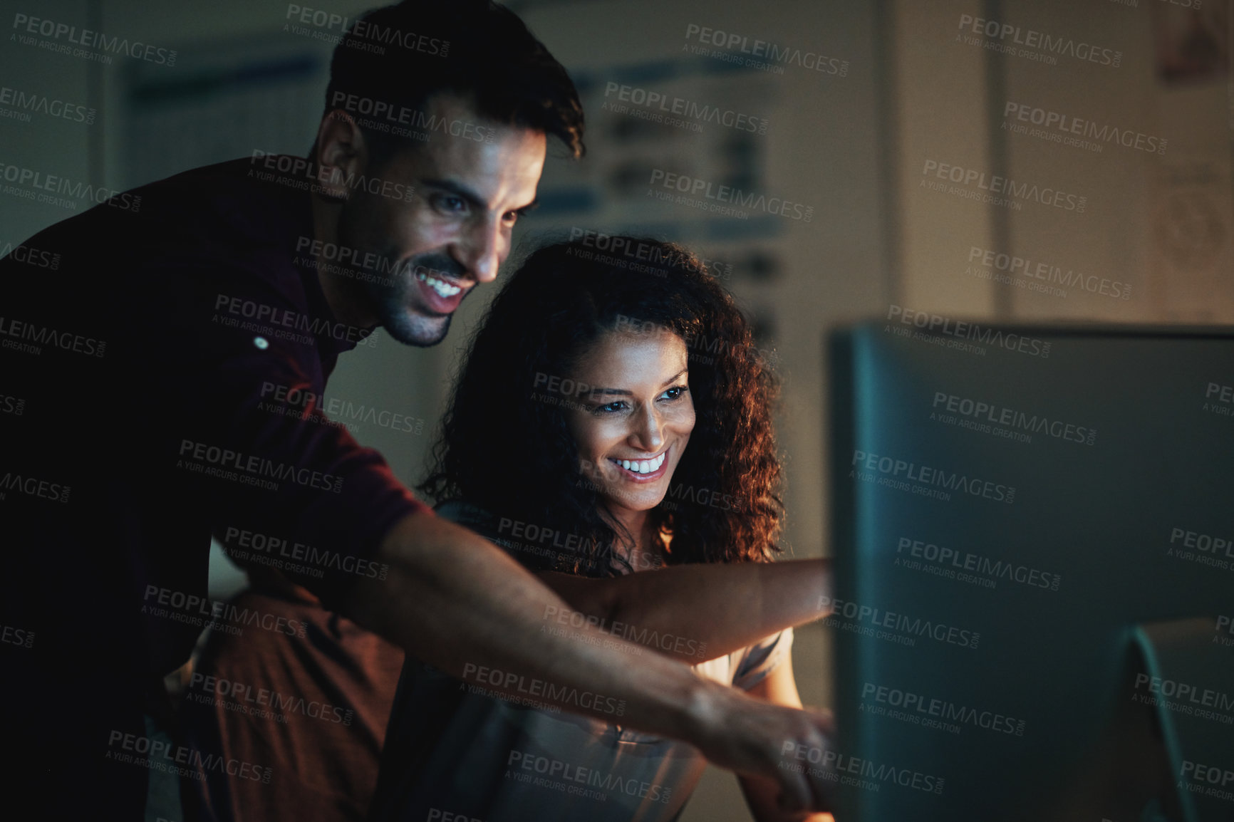 Buy stock photo Shot of two colleagues using a computer together during a late night at work