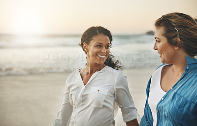 Buy stock photo Shot of a loving couple walking hand in hand on the beach