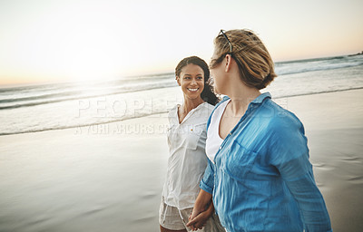 Buy stock photo Shot of a loving couple walking hand in hand on the beach