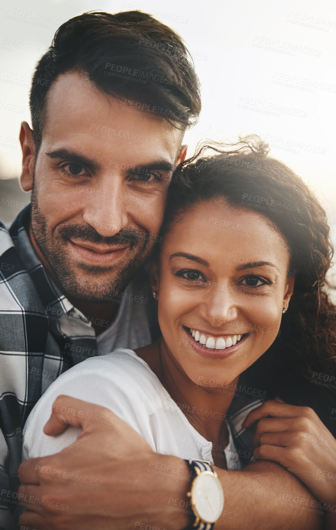 Buy stock photo Shot of a young man hugging his girlfriend from the back while spending the day outdoors