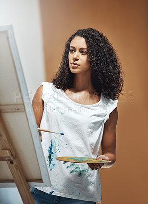 Buy stock photo Shot of an attractive young woman painting on a canvas at home