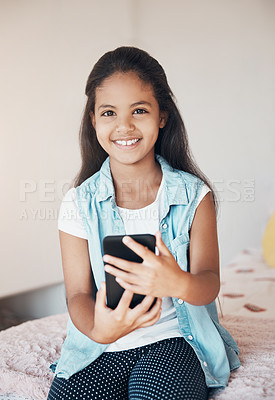 Buy stock photo Shot of a happy young girl sitting on her bed and using a mobile phone at home