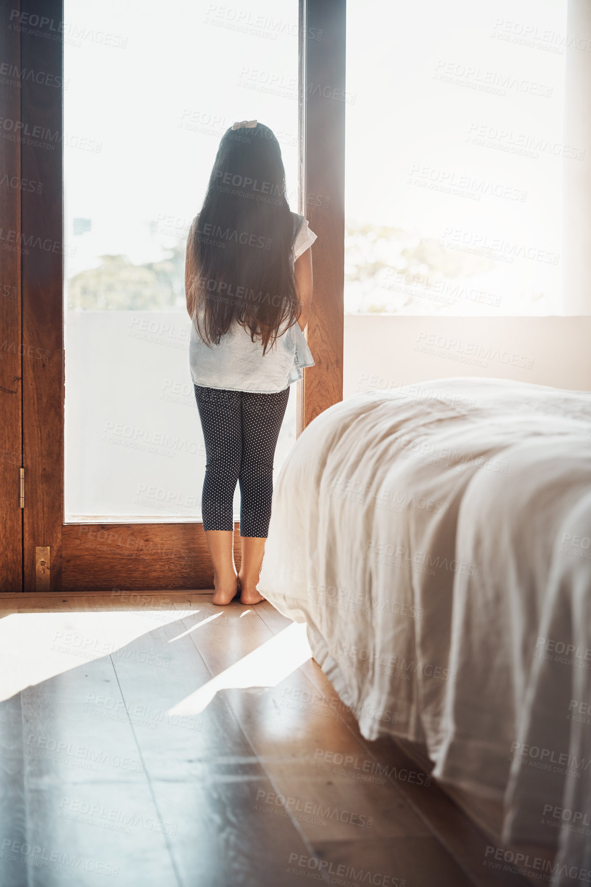 Buy stock photo Rearview shot of a young girl looking out of the window at home