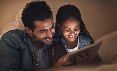 Buy stock photo Shot of a father and his daughter using a digital tablet together at bedtime
