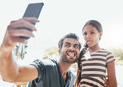 Buy stock photo Shot of a father and his daughter taking fun selfies together on a mobile phone
