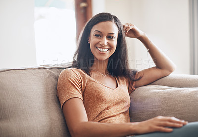 Buy stock photo Shot of a happy young woman enjoying a relaxing day on the sofa at home