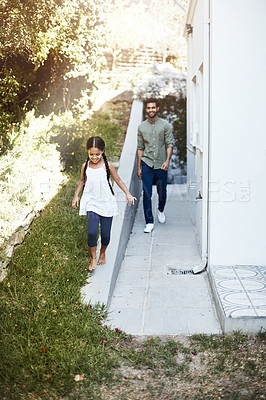 Buy stock photo Shot of a happy young girl going for a walk in the backyard with her father behind her