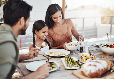 Buy stock photo Shot of a happy young family enjoying a meal together outdoors