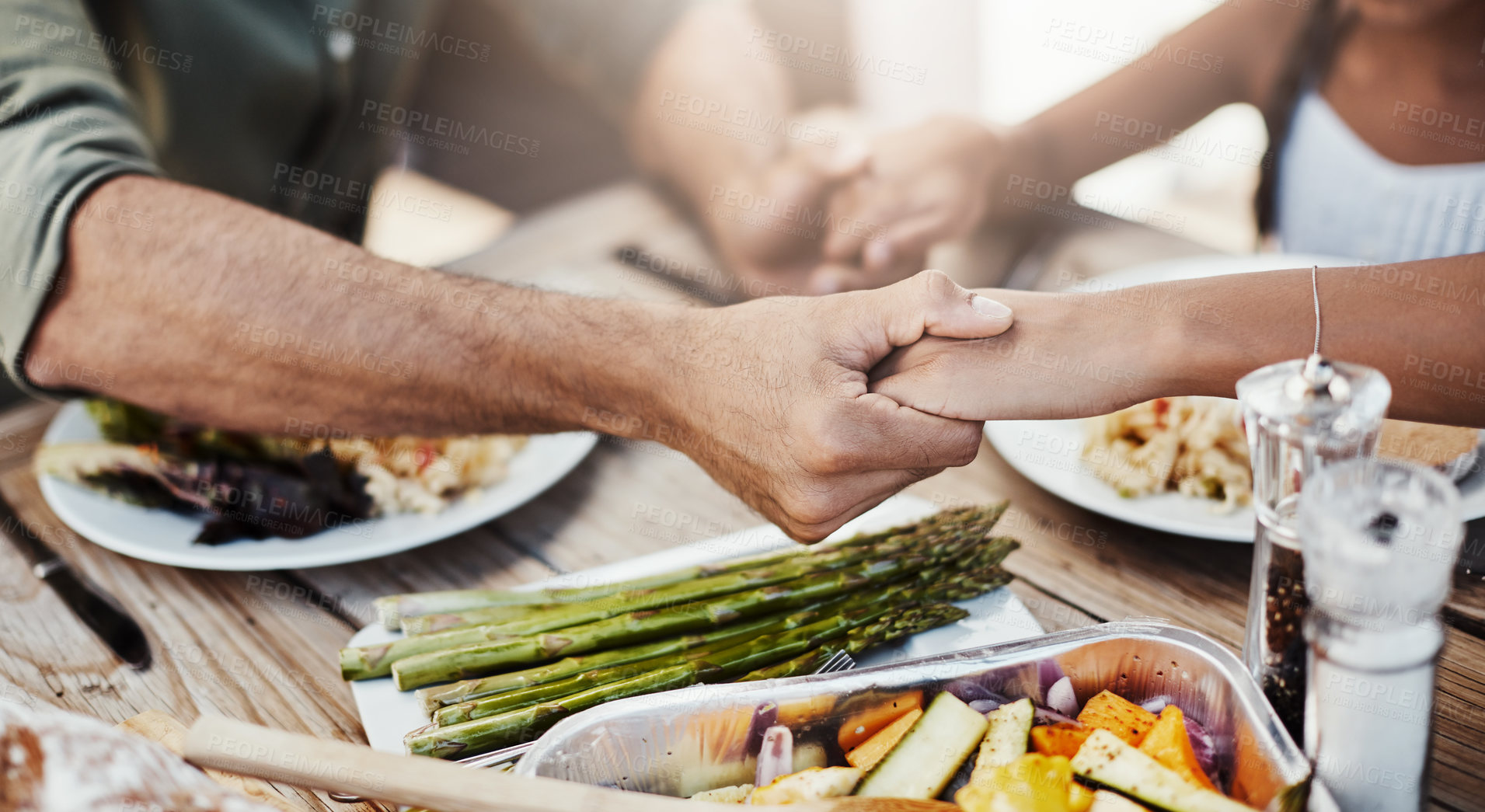 Buy stock photo Cropped shot of a family holding hands in prayer before having a meal together