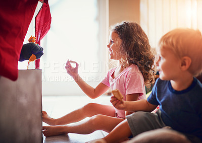 Buy stock photo Shot of two little siblings watching a puppet show at home