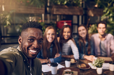 Buy stock photo Shot of a young man taking a selfie while out with friends at a cafe