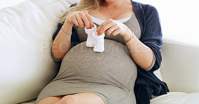 Buy stock photo Shot of an unrecognizable pregnant woman holding baby booties on her belly at home