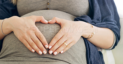 Buy stock photo Shot of a pregnant woman making a heart frame on her belly at home