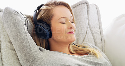 Buy stock photo Shot of an attractive young woman listening to music with headphones at home