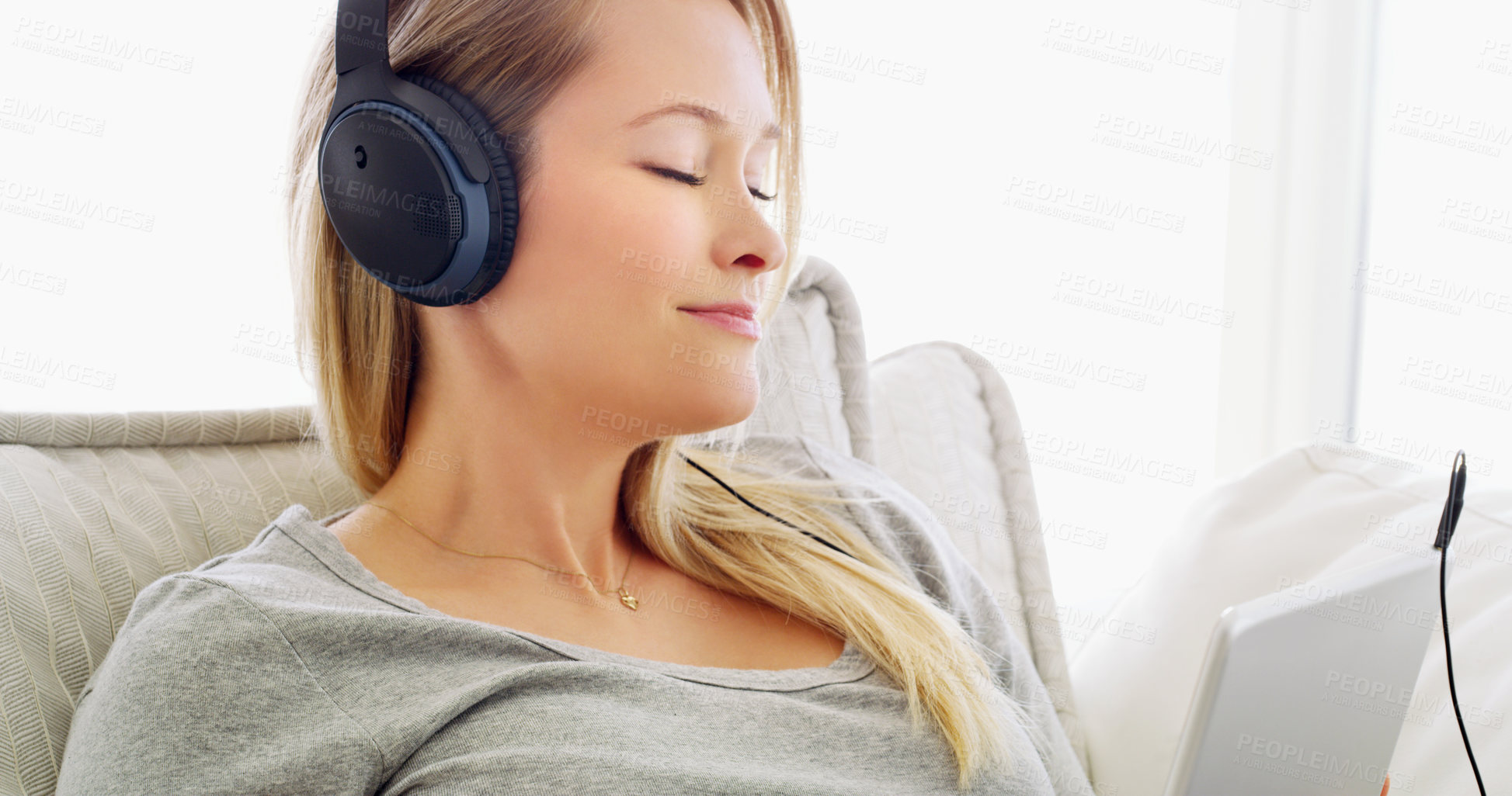 Buy stock photo Shot of an attractive young woman listening to music with headphones at home