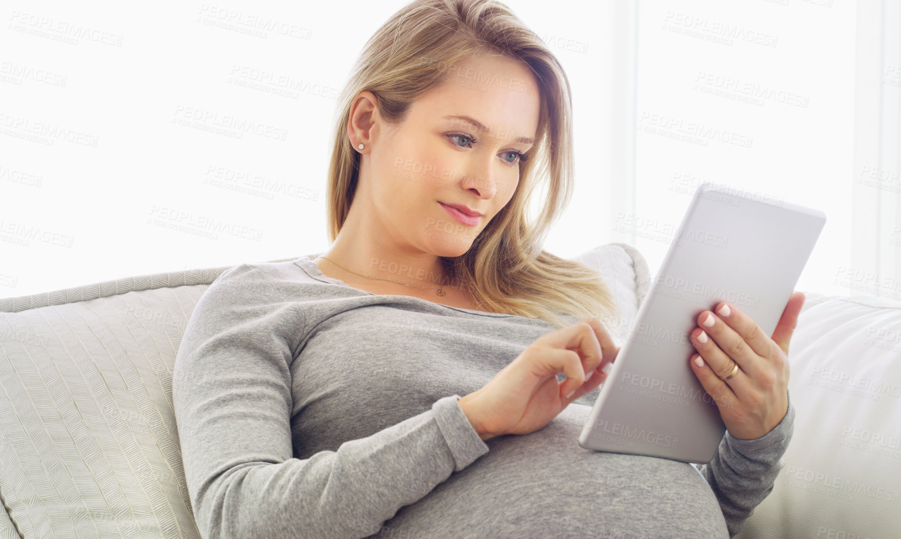 Buy stock photo Shot of a pregnant woman using a tablet at home