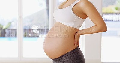 Buy stock photo Cropped portrait of an unrecognizable young pregnant woman standing with her hands on her back