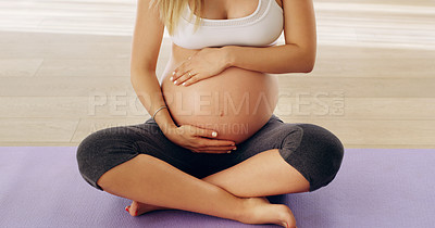Buy stock photo Cropped shot of an unrecognizable young pregnant woman rubbing her baby bump while sitting on a yoga mat