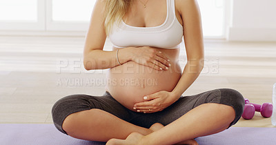Buy stock photo Cropped shot of an unrecognizable young pregnant woman rubbing her baby bump while sitting on a yoga mat