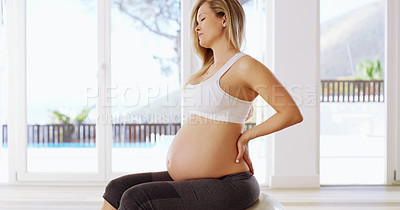 Buy stock photo Cropped shot of an attractive young pregnant woman sitting with her hands on her back