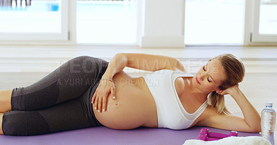 Buy stock photo Cropped shot of an attractive young pregnant woman lying on her side on a yoga mat