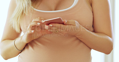 Buy stock photo Cropped shot of an unrecognizable pregnant woman using a cellphone at home