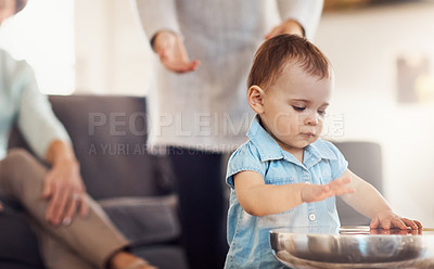 Buy stock photo Shot of an adorable baby girl banging playfully on a table with her family in the background