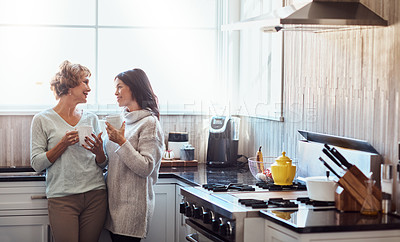 Buy stock photo Shot of a young woman enjoying a coffee break and chat in the kitchen with her mother at home