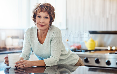 Buy stock photo Shot of a mature woman enjoying a warm beverage in the kitchen at home