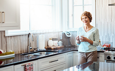 Buy stock photo Shot of a mature woman enjoying a warm beverage in the kitchen at home