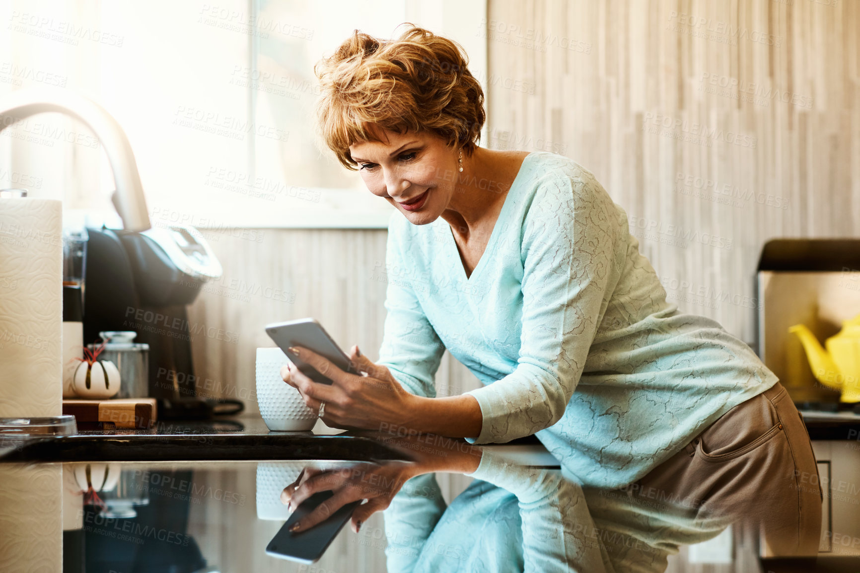 Buy stock photo Phone, reading and senior woman in kitchen with smile, connection or scroll on social media. Morning, relax and elderly person in home with smartphone, online chat or mobile app for communication