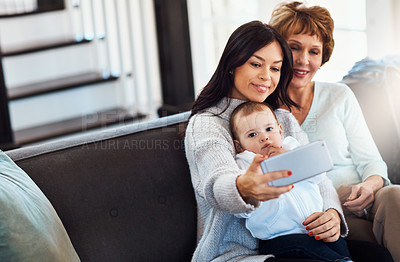 Buy stock photo Shot of a young woman taking selfies with her baby girl and mother at home