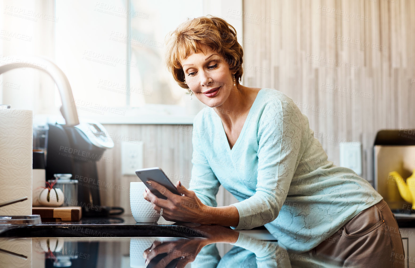 Buy stock photo Smartphone, reading and senior woman in kitchen with smile, connection or scroll on social media. Morning, relax and elderly person in home with phone, online chat or mobile app for communication