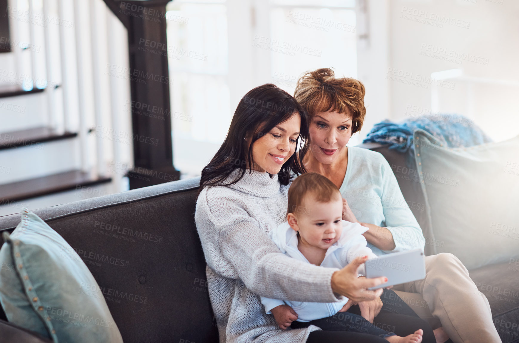 Buy stock photo Shot of a young woman taking selfies with her baby girl and mother at home