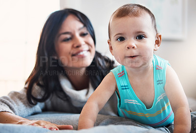 Buy stock photo Shot of an adorable baby girl crawling on a bed with her mother in the background