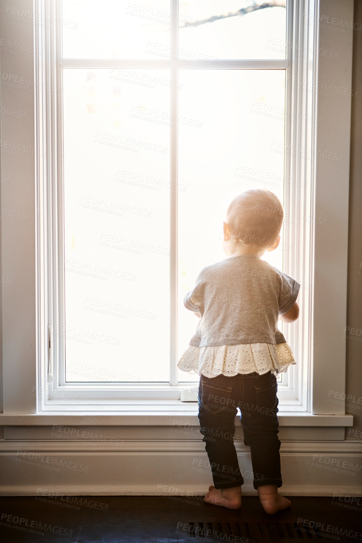 Buy stock photo Rearview shot of an adorable little girl looking out of the window at home