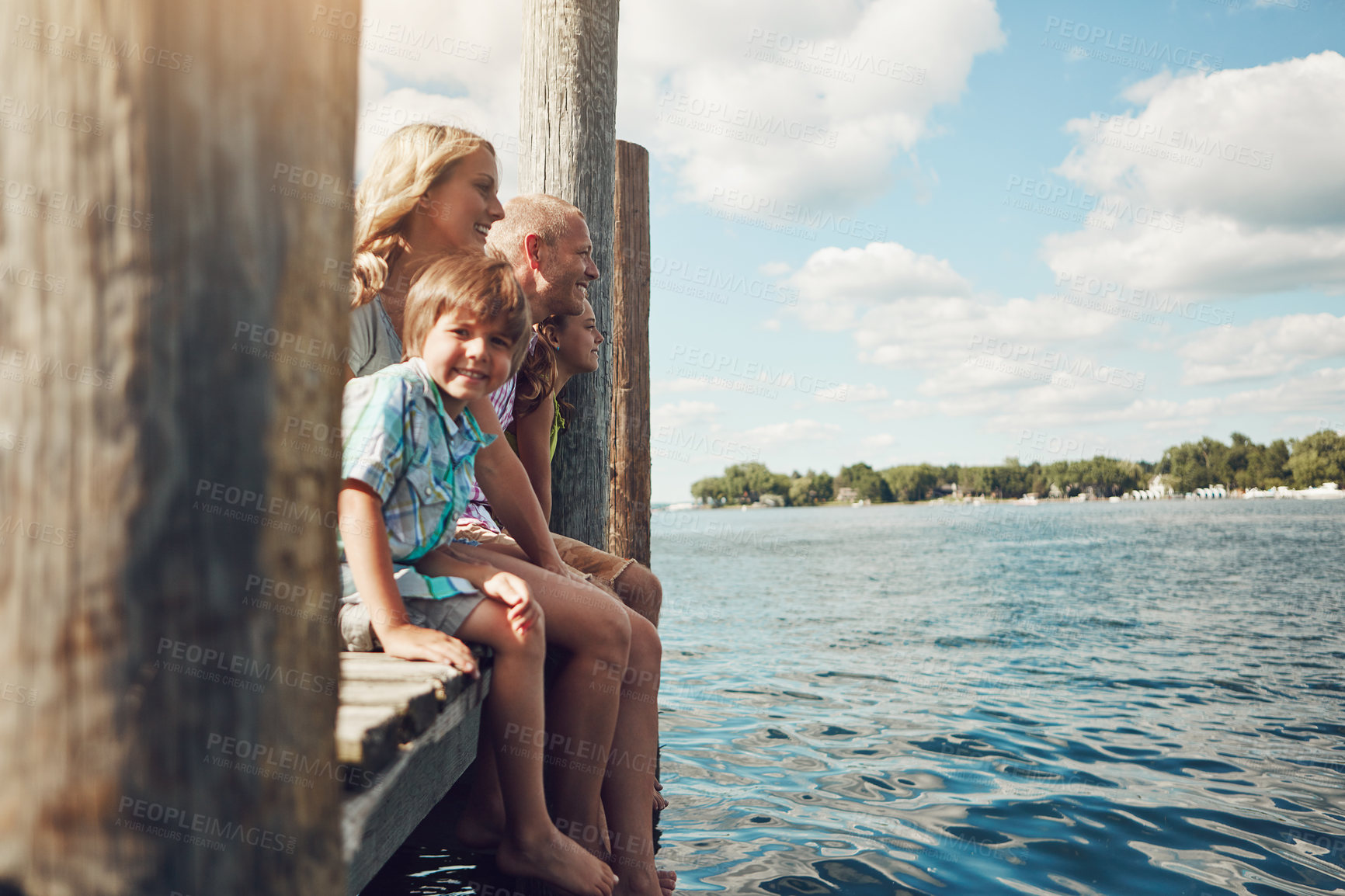 Buy stock photo Shot of a young family on a pier while out by the lake