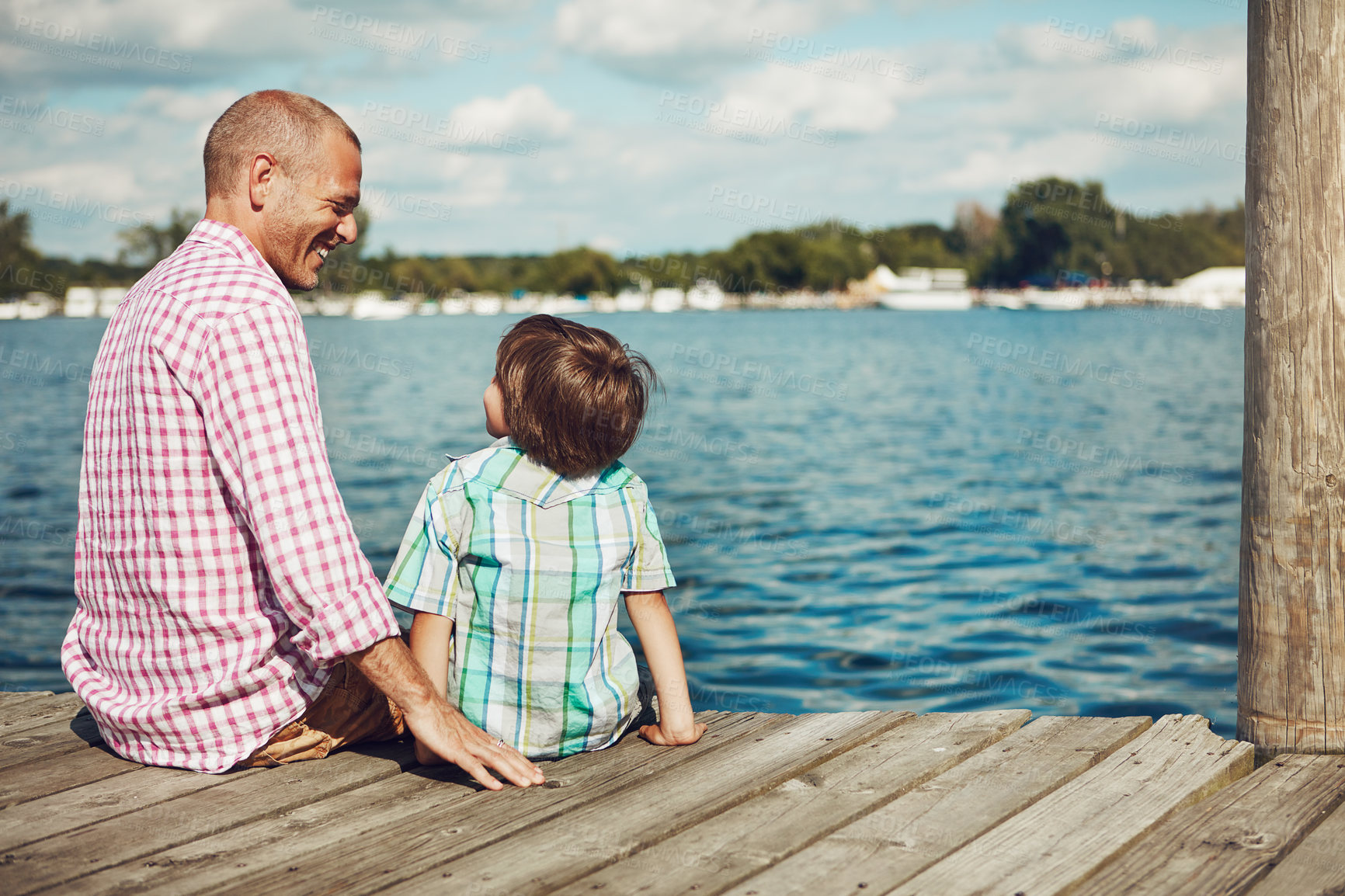 Buy stock photo Shot of a young father and son on a pier while out by the lake