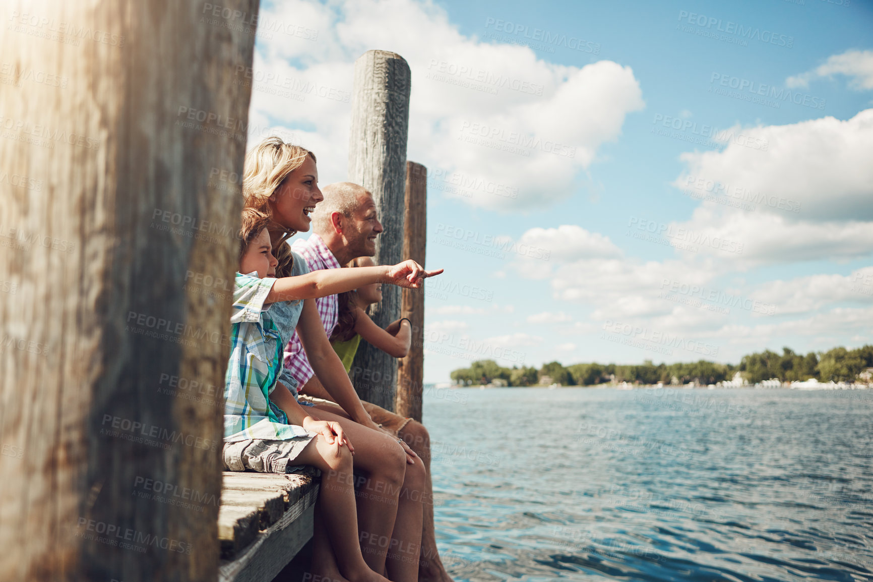 Buy stock photo Family, vacation and relax at jetty by lake for travel, adventure or sightseeing with parents. Kids, mom and dad by water deck outdoor for holiday, bonding together and pointing at view with smile