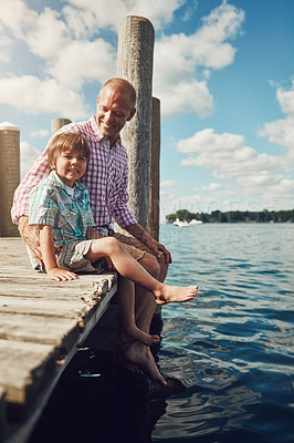 Buy stock photo Shot of a young father and son on a pier while out by the lake